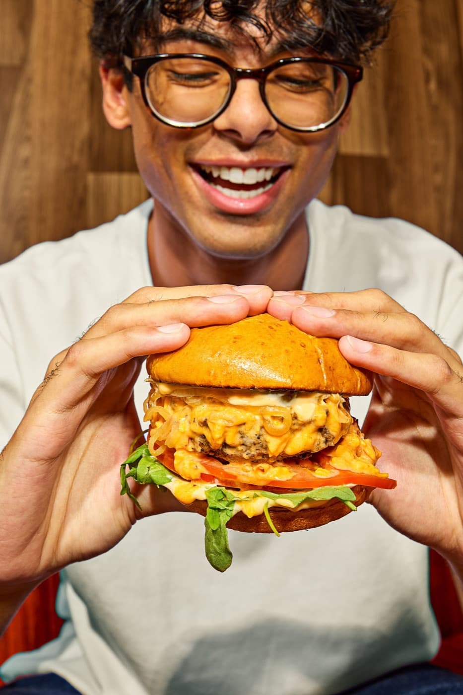 Guest holding a saucy GoodHood burger with both hands