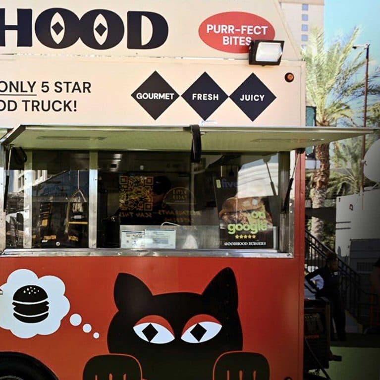 The GoodHood trailer at an event, windows open, with the cat peeking over the side